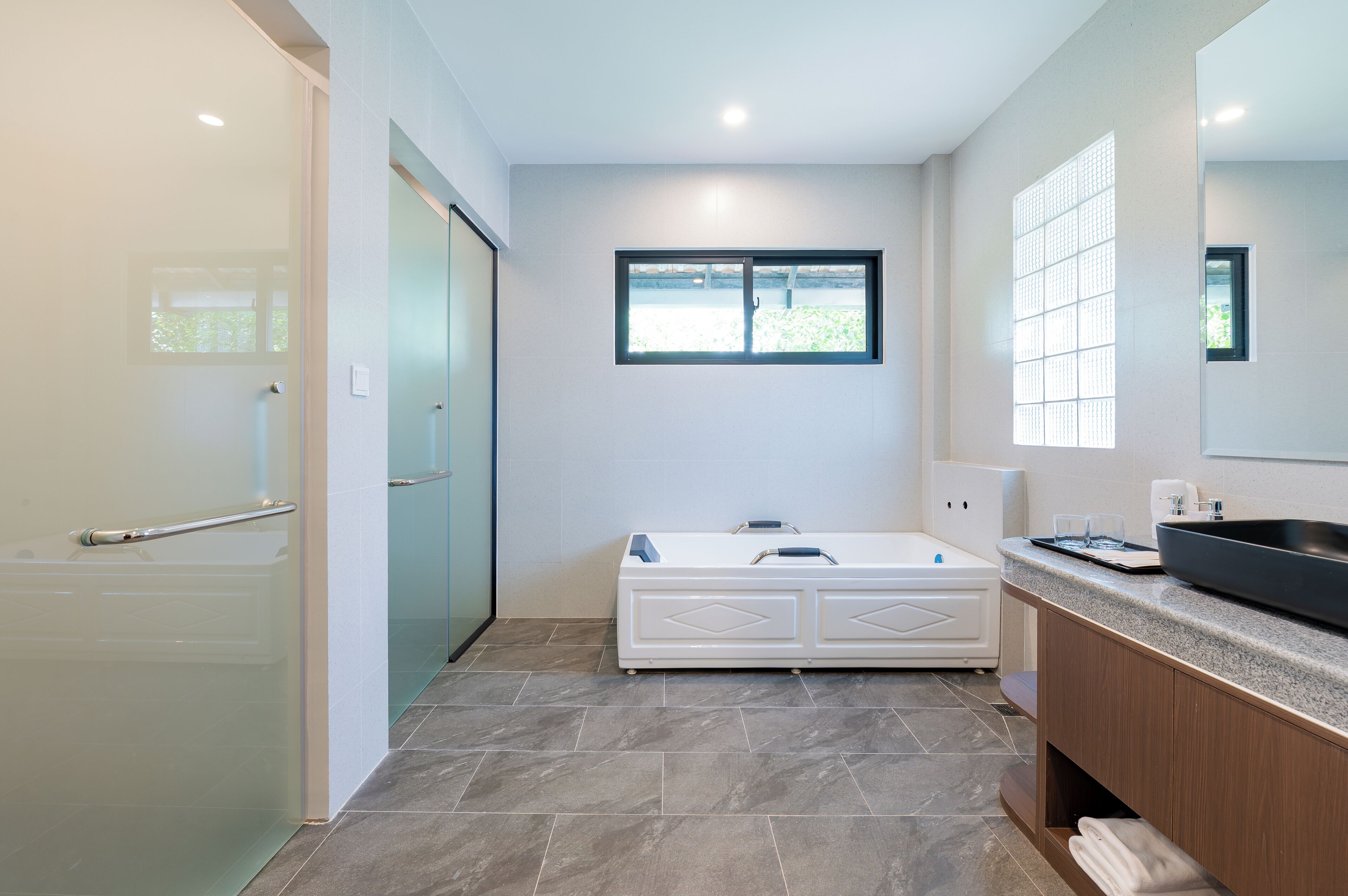 A modern bathroom with a glass shower enclosure, a freestanding bathtub, and a large mirror.