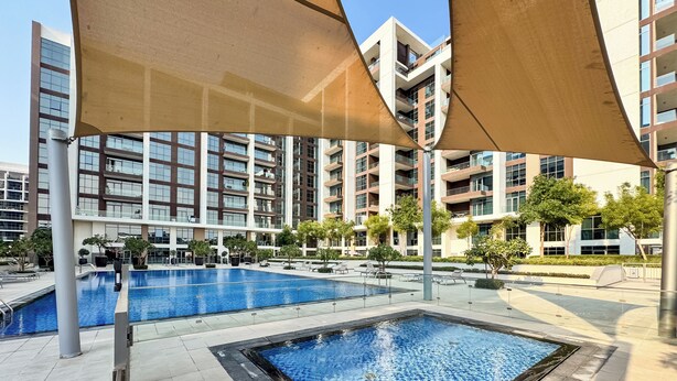 Ein moderner Poolbereich mit einem rechteckigen Pool und einem kleineren quadratischen Pool, umgeben von einer angelegten Terrasse mit Topfpflanzen und Liegestühlen.