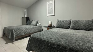 Ein Schlafzimmer mit zwei Betten, einem kleinen Tisch und einem Wandbild.