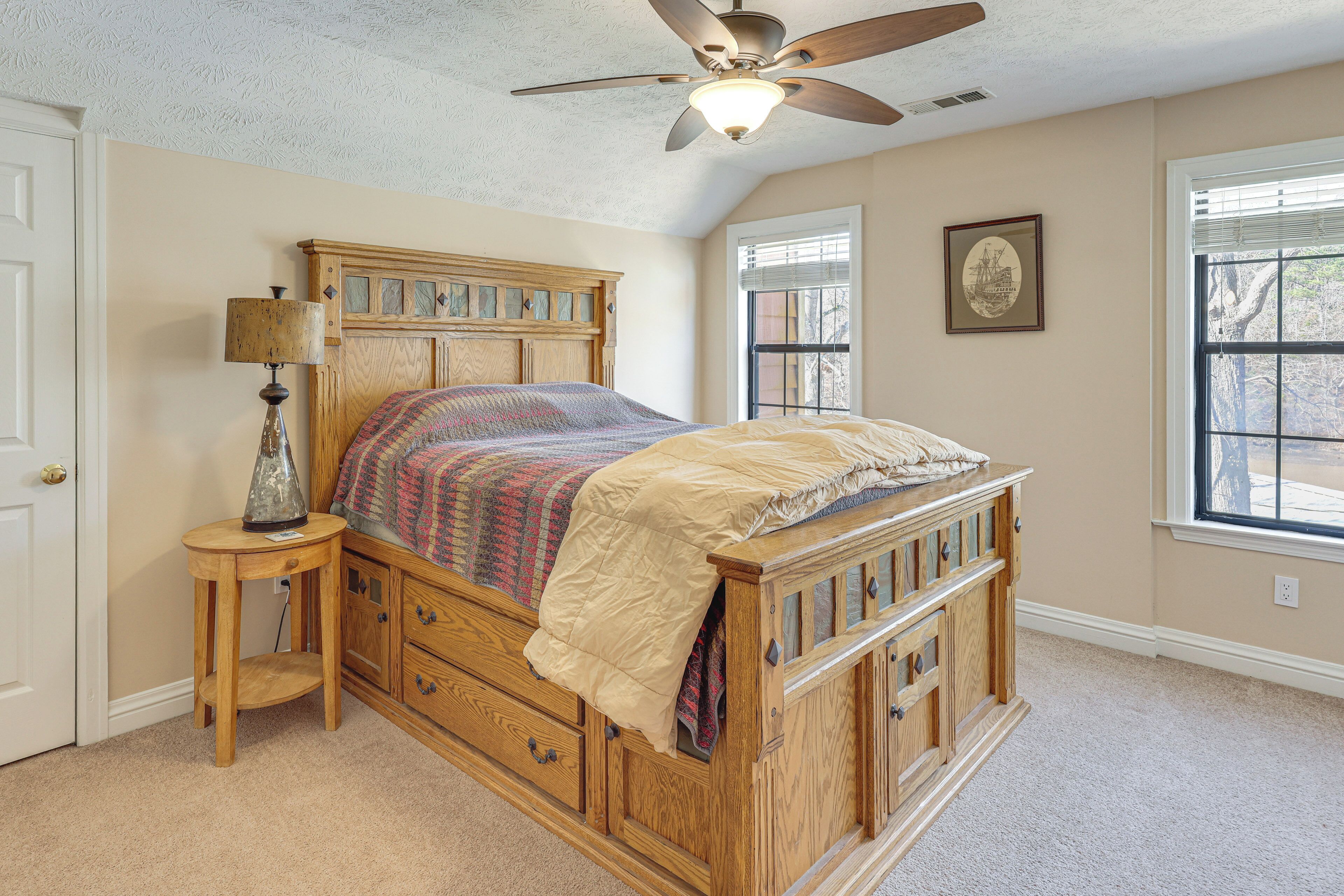 A bedroom with a wooden bed, a nightstand, a ceiling fan, and a window with blinds.