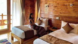 A wooden cabin room with two beds, a window with curtains, and a wooden floor. - Sonam Zhidhey Resort  (Ha)