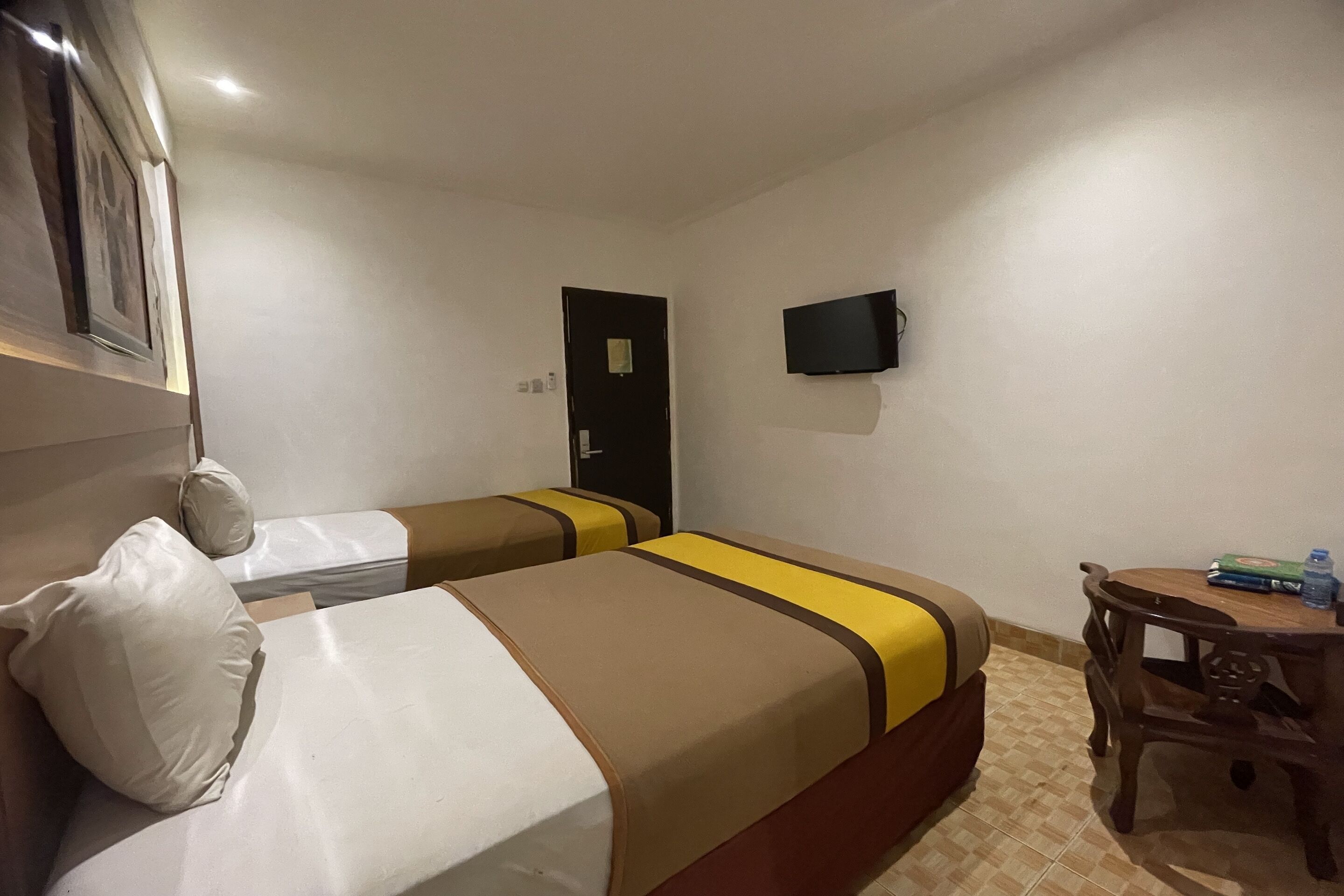 Ett hotellrum med två sängar, en tv, ett litet bord och en dörr.