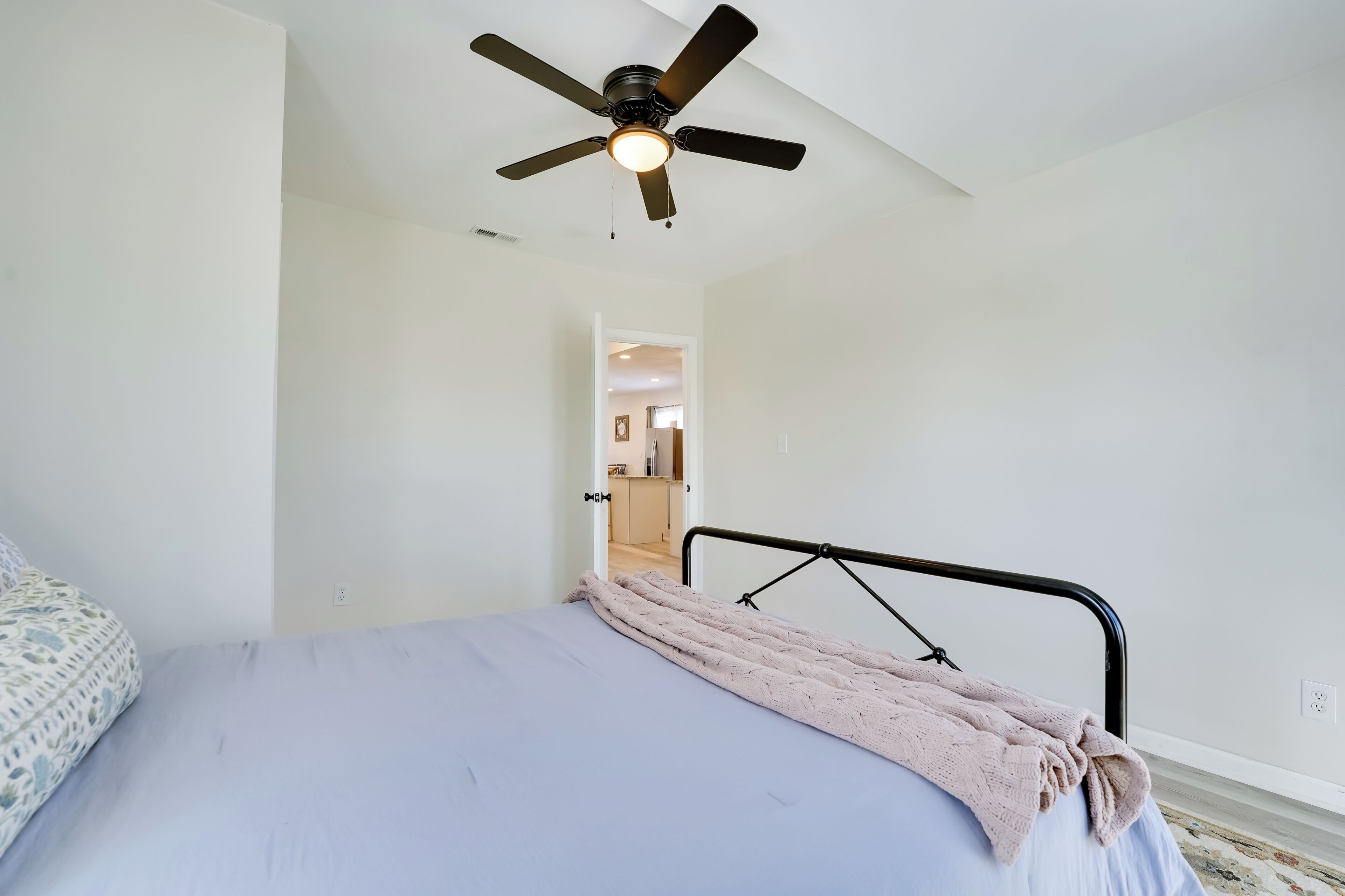 Ein Schlafzimmer mit einem Bett, einem Deckenventilator und einer Tür zu einem Badezimmer.