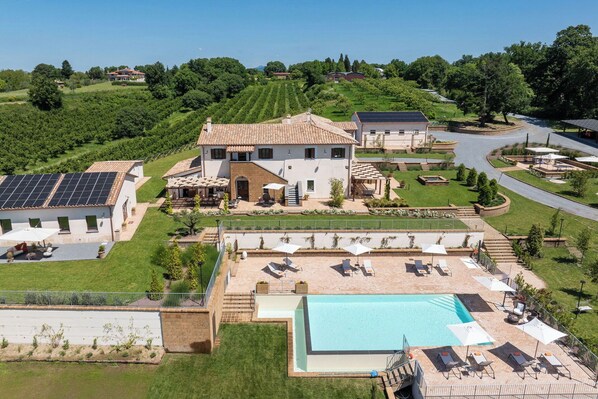A large villa with a swimming pool, solar panels, and a landscaped garden.
