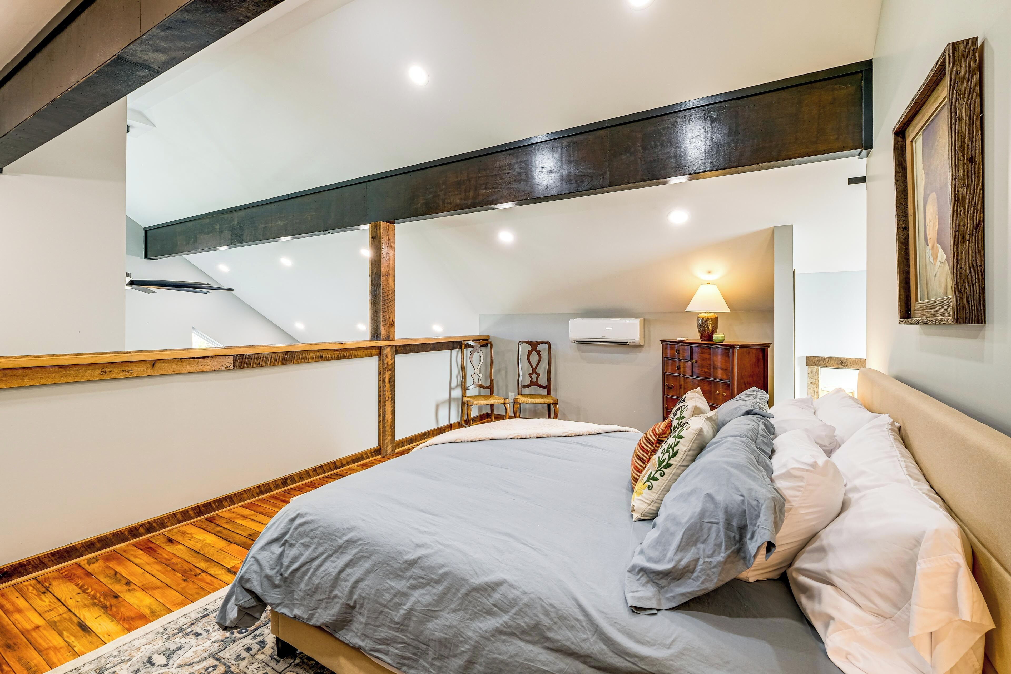 Une chambre à coucher avec un lit, un plancher en bois et un escalier.