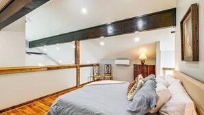 Un dormitorio con cama, suelo de madera y una escalera.