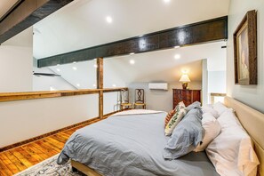 A bedroom with a bed, wooden floor, and a staircase. - Peaceful Farmhouse Retreat 6 Mi to Virginia Tech! (Blacksburg)
