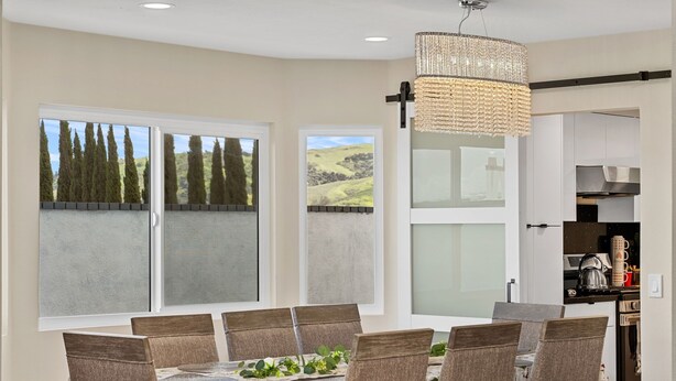 A dining area with a table set for six, large windows with a view of trees and hills, and a kitchen area with modern appliances. - Relax & Unwind: Pool, Jacuzzi & Private Backyard (Rowland Heights)