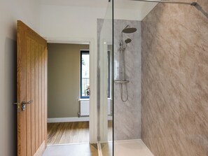Une salle de bain moderne avec une douche à parois de verre, une porte en bois et une vue sur une pièce dot ée d’une fenêtre.