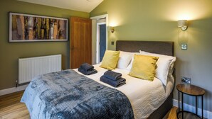 A bedroom with a bed, a radiator, a door, and a painting on the wall. - Lakeside Lodge - UK50627 (Welshpool)