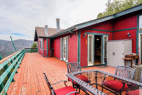 A red wooden building with a balcony, metal chairs, and a glass table. - Private Sauna & Mtn-View Deck! Kern County Home (Pine Mountain Club)