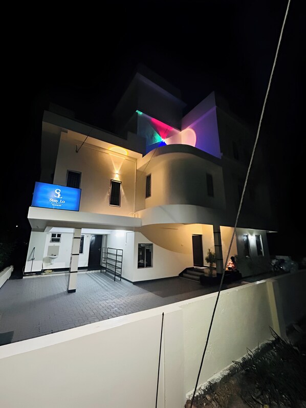 A modern two-story house with a flat roof and a balcony.