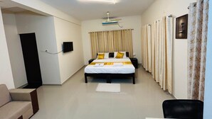 Moderni hotellihuone, jossa on sänky, työp öytä, tuoli, kattotuuletin ja televisio.