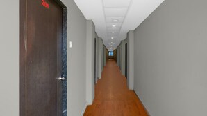 A long, narrow hallway with wooden flooring and grey walls. - Hotel O Vapi Gidc Formerly Zion Inn (Vapi)