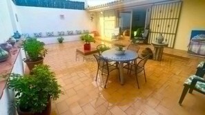 Un espace patio avec une table ronde et des chaises, entouré de plantes en pot.