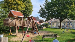 A wooden play structure, a swing set, and a covered playhouse in a grassy yard.