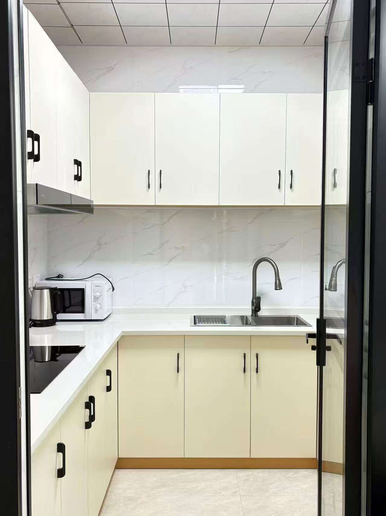 A modern kitchen with white cabinets, a black countertop, a built-in microwave, and a stainless steel sink.