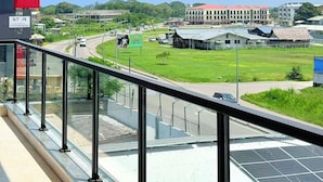 A view from a balcony overlooking a road with a building in the background.