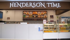 A bar area with a sign reading 'HENDERSON TIME' and a display of various liquor bottles.