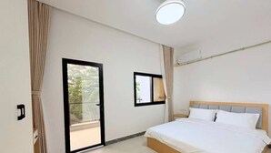 A bedroom with a bed, a window, a door, and a ceiling light.
