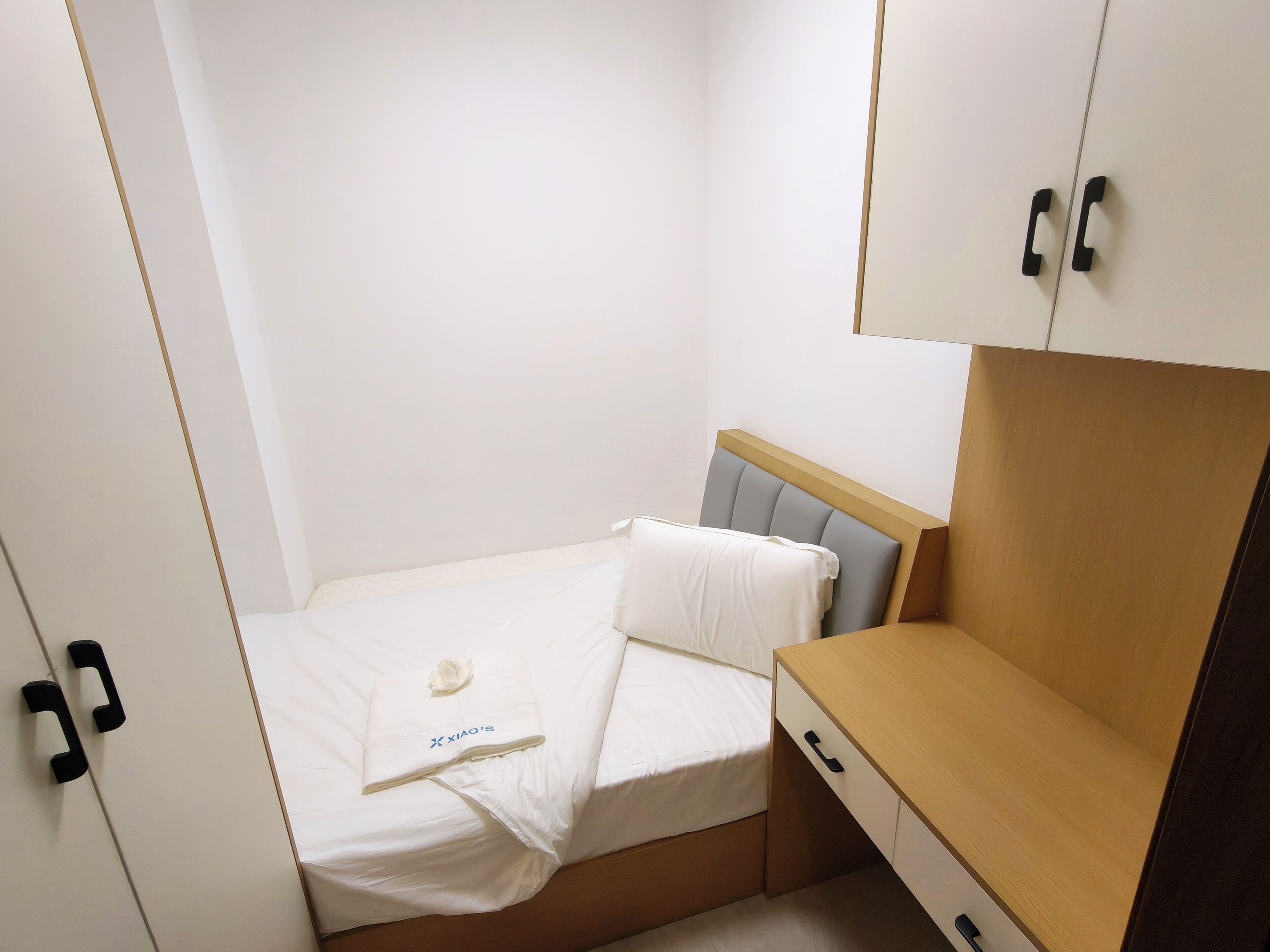 Un dormitorio pequeño y ordenado con cama, un escritorio de madera y un armario.