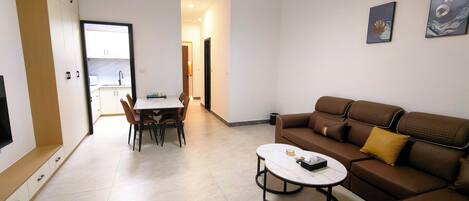 A modern living room with a brown sofa, a coffee table, and a dining area with chairs and a table.
