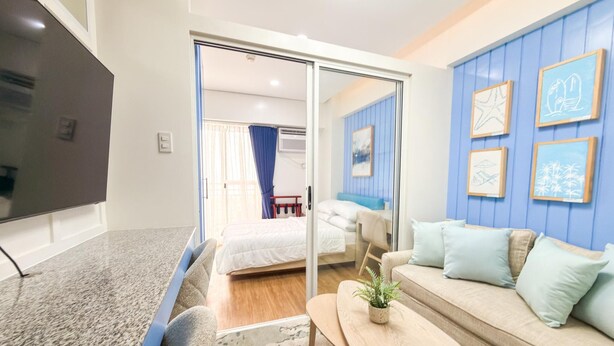 A modern hotel room with a flat-screen TV, a sofa, a small table, and a bed. - Maree- Verdon Parc, Davao City (Davao City)