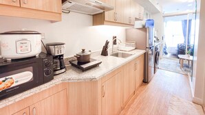 A modern kitchen with wooden cabinets, a built-in stove, a coffee maker, and a refrigerator. - Maree- Verdon Parc, Davao City (Davao City)