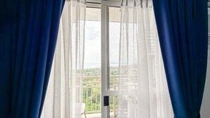 A room with a balcony, white curtains, and a view of greenery. - Maree- Verdon Parc, Davao City (Davao City)