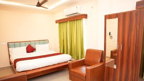 Habitación de hotel con cama, una silla, armario y aire acondicionado.