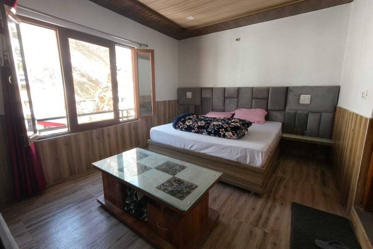 A bedroom with a bed, a glass-top table, a bench, and a window.