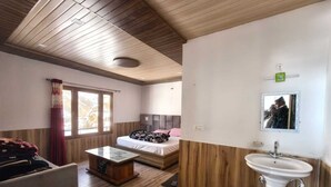 A room with a bed, a small table, a sink, and a window. - Hotel Yamuna Palace (Gurugram)