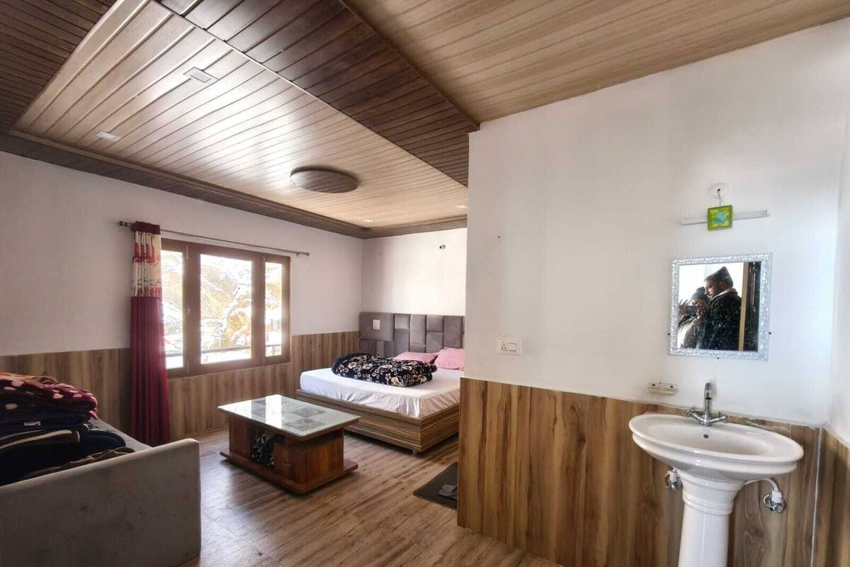 A room with a bed, a small table, a sink, and a window.