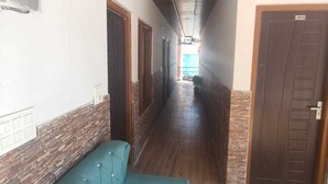A hallway with a wooden ceiling, a blue sofa, and doors numbered 205 and 206. - Hotel Yamuna Palace (Gurugram)