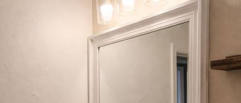 A bathroom with a white sink, a mirror, and a towel dispenser.