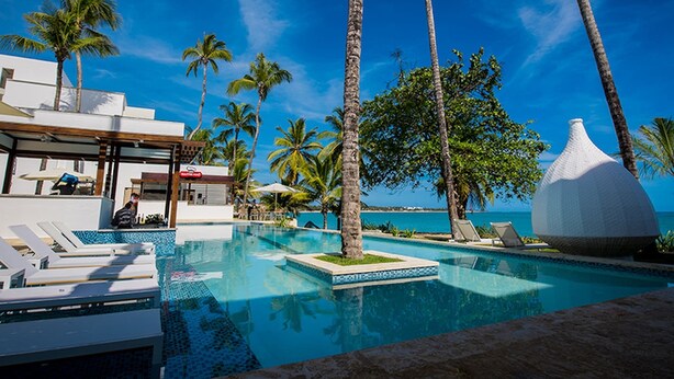 A pool area with lounge chairs, palm trees, and a modern building with a white dome structure. - Presidencial suite 2 bedroom and kitchen Cabarete (Cabarete)