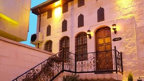 A building with a staircase, potted plants, and a balcony with wrought iron railings. - Hurşitbey Konağı (Gaziantep)