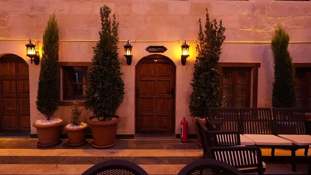A building with a sign reading 'Mihriye Sultan,' wooden doors, potted plants, outdoor seating with tables and chairs, and wall-mounted lanterns. - Hurşitbey Konağı (Gaziantep)