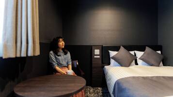 A hotel room with a bed, a round table, and a person sitting at the table.