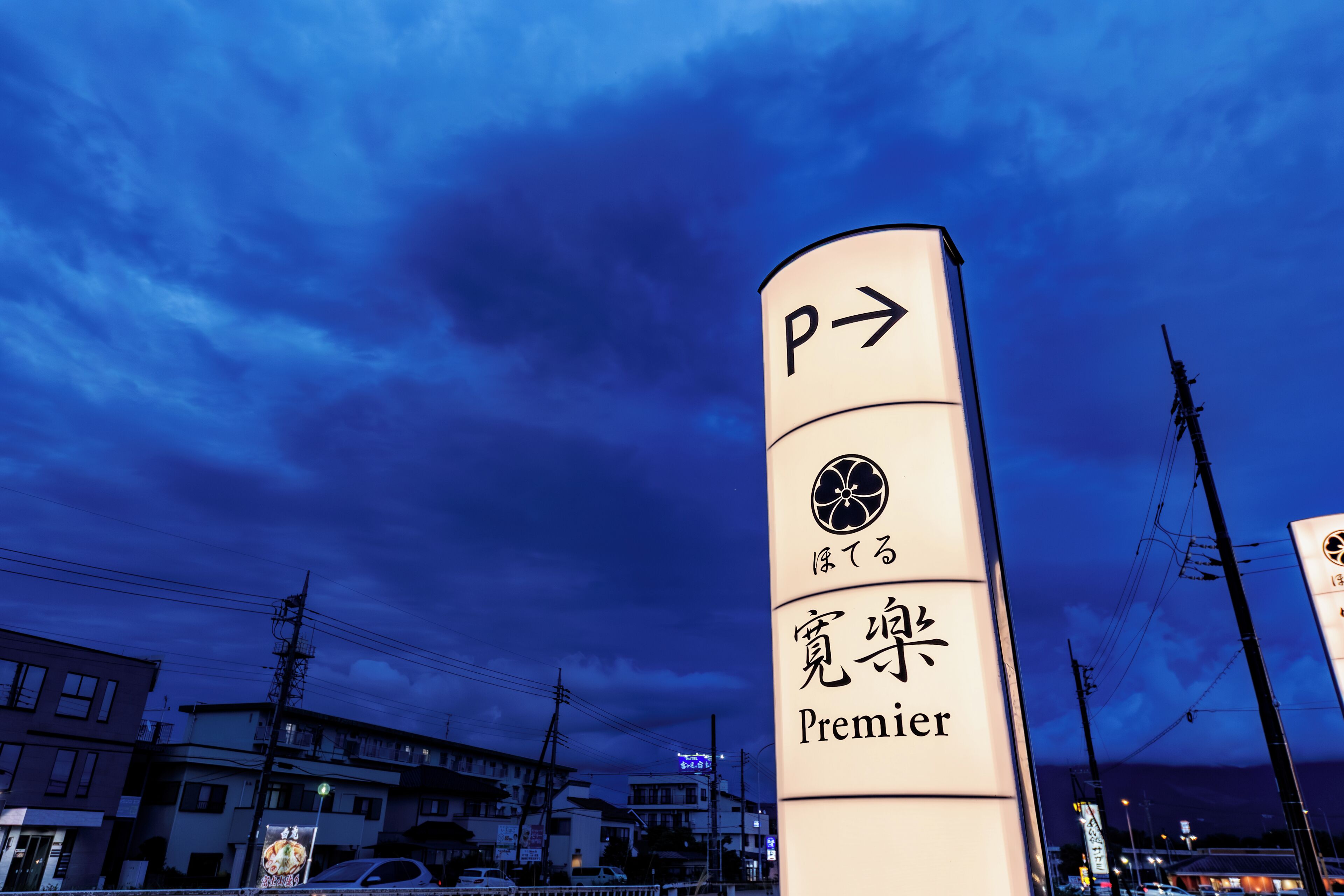 A tall sign with a 'P' and an arrow indicating a direction, with Japanese characters and the word 'Premier' below.