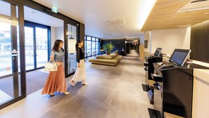 Vestíbulo de hotel con mostrador de recepción, zona de estar y amplios ventanales.