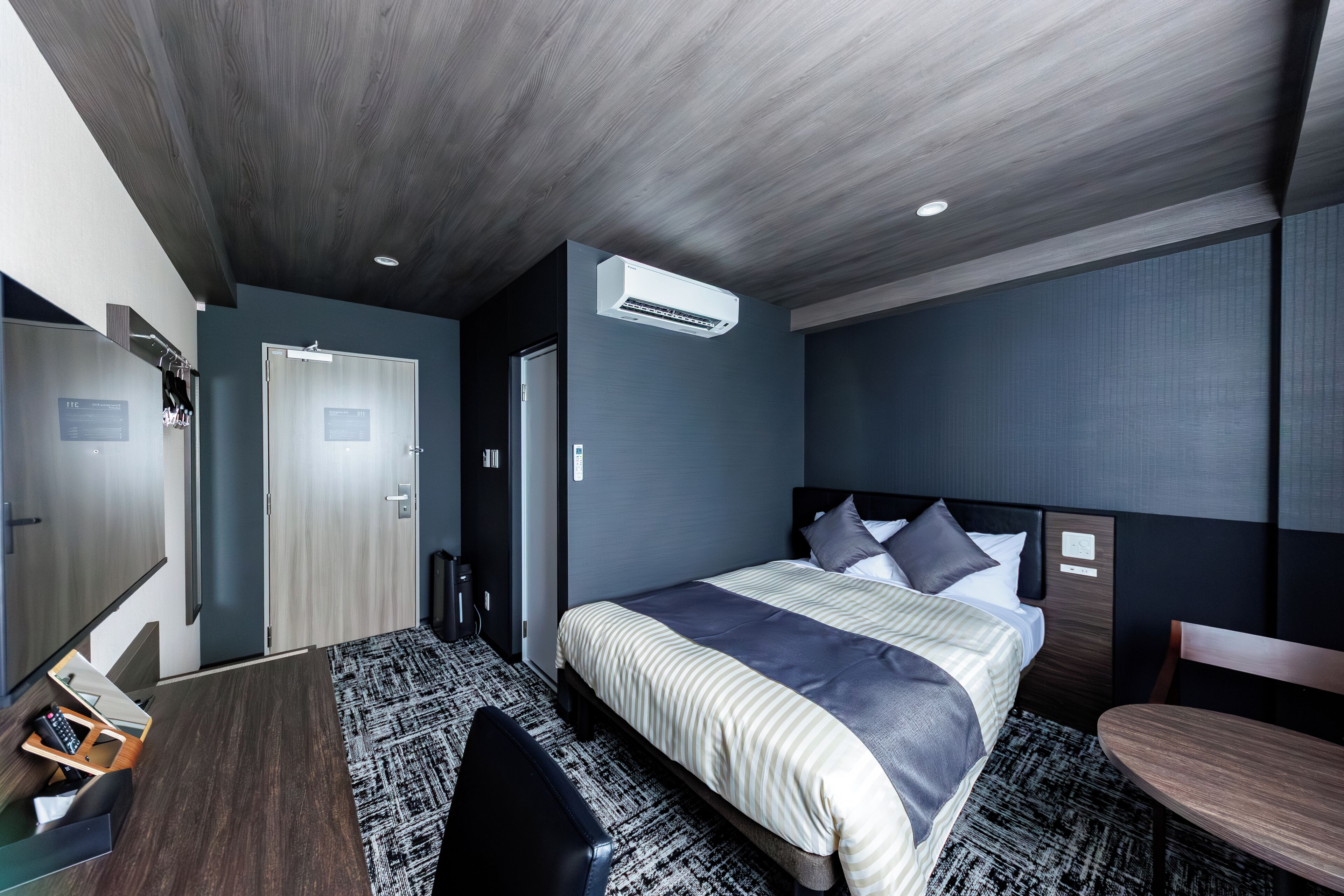 Une chambre d’hôtel moderne équipée d’un lit, d’un bureau, d’une chaise et d’une petite table.