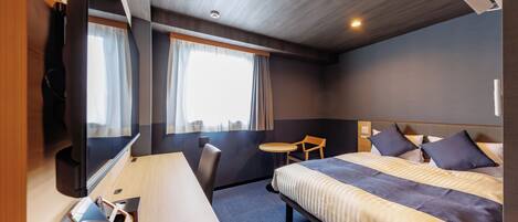Una habitación de hotel con cama, escritorio, silla, mesita y televisión.