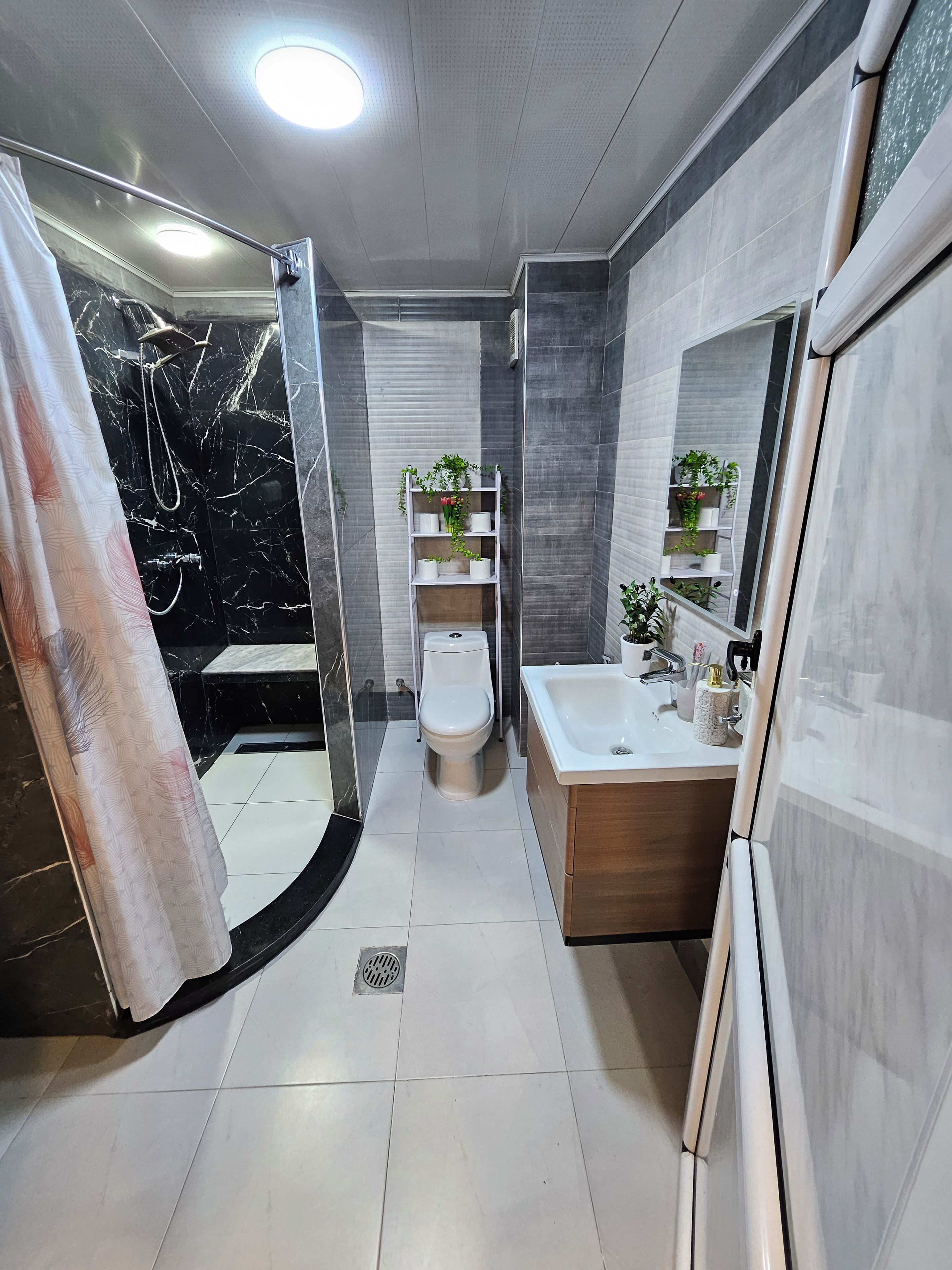 Een moderne badkamer met douche, toilet en wastafel.