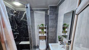 Et moderne badeværelse med bruser, toilet og håndvask.