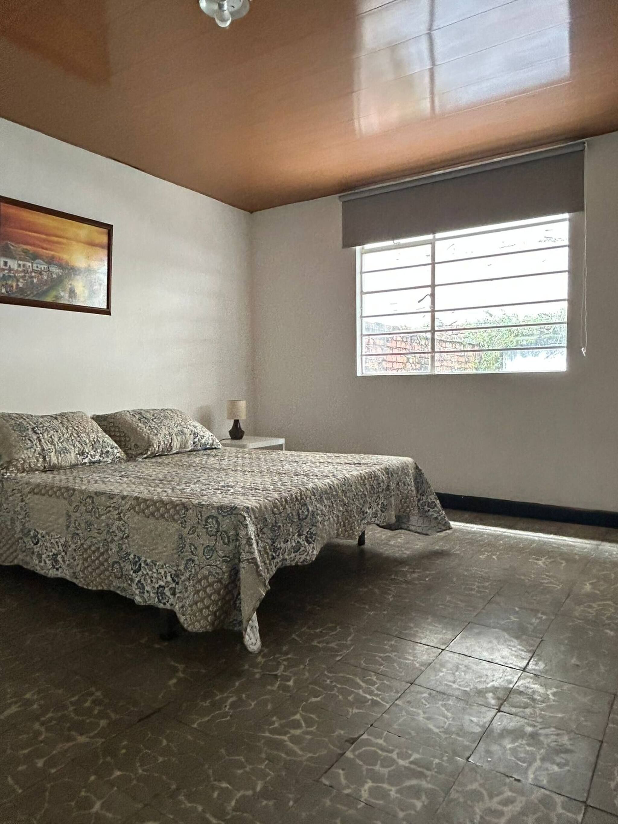 Une chambre à coucher avec un lit, une fenêtre et un tableau accroché au mur.