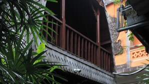 A traditional building with a tiled courtyard, potted plants, and a wooden balcony. - Tusantha Ubud A Trishula Collection (Ubud)