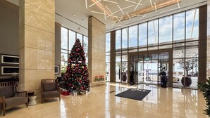 A spacious lobby with a large Christmas tree, modern lighting, and a view of the outside through large windows. - PVH - The8 - Opulent 3BR - Beach Access (Dubai)