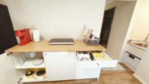 Cucina compatta con piano di lavoro in legno, pensili e piccolo lavello.