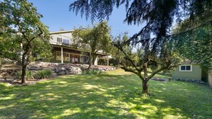 Una casa con un ampio giardino anteriore, un muro di sostegno in pietra e un albero sullo sfondo.